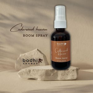 May include: A brown glass bottle with a white spray nozzle. The bottle is labelled "bodhi AROMAS Cedarwood Haven Room Spray 1.7 oz | 50 ml".