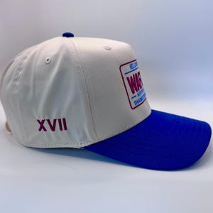 Puede incluir: Gorra de b&eacute;isbol con corona crema y visera azul. La gorra presenta un parche rectangular con la palabra "WAR" en texto rojo y azul. El n&uacute;mero romano "XVII" est&aacute; bordado en el lateral.
