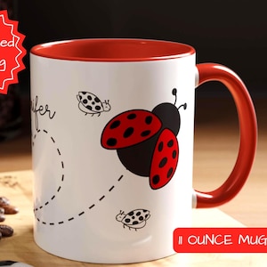 May include: White ceramic mug with a red rim and handle. The mug features a black and red ladybug design with the text "Jennifer" and "11 ounce mug".