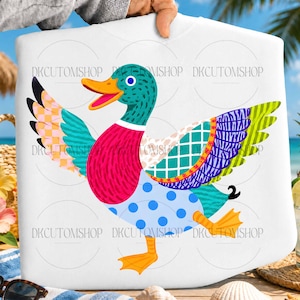 Op de afbeelding: Wit T-shirt met een kleurrijk eendenontwerp. De eend heeft een turquoise kop, een roze borst en een blauwe broek met stippen. Het heeft oranje voeten en een gele snavel. Het ontwerp is levendig en geschikt voor een casual stijl.