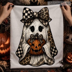 May include: A white fabric square featuring a central illustration of a ghost with a cracked texture, wearing a large checkered and leopard print bow. The ghost holds a carved orange jack-o'-lantern with a matching leopard print bow.