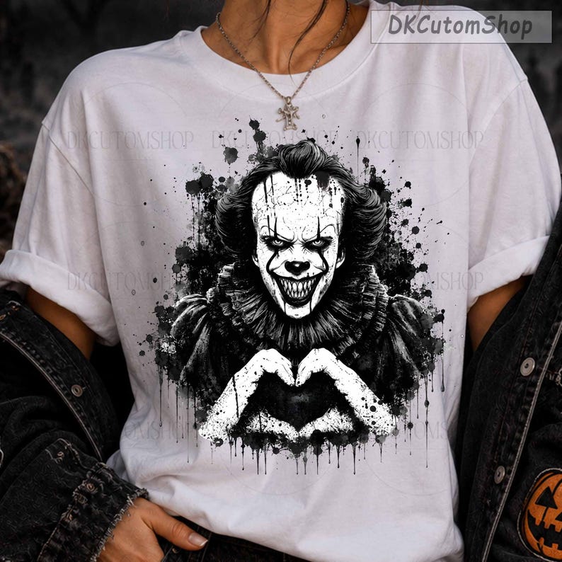 May include: A white t-shirt featuring a black and white graphic print of a clown with sharp teeth and a ruffled collar, making a heart shape with hands. The design includes ink splatter effects and the text DKCutomShop in the top right corner.