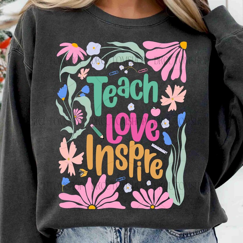 May include: A dark gray sweatshirt with a colorful floral design and the text "Teach Love Inspire".