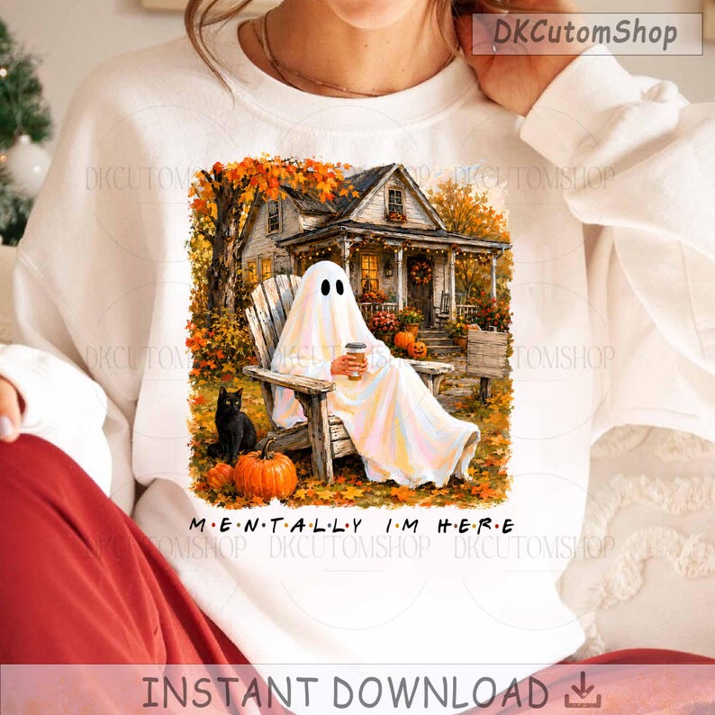 Op de afbeelding: Een wit sweatshirt met ronde hals en een grafische print van een geest die op een houten stoel op een veranda zit en een koffiebeker vasthoudt. Een zwarte kat en oranje pompoenen zijn zichtbaar. De tekst MENTALLY I'M HERE staat onder de afbeelding.