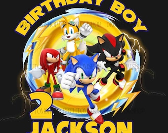 May include: A birthday party design featuring Sonic the Hedgehog, Tails, Knuckles, and Shadow the Hedgehog. The design is yellow, blue, red, and black with a lightning bolt pattern. The text "Birthday Boy" and "Jackson" are in yellow. The number "2" is in yellow and blue.