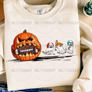 May include: Cream-colored sweatshirt featuring a large orange pumpkin with a football design and a menacing face. Three cartoon ghosts are depicted playing hockey, baseball, and football. The text "DKCUTOMSHOP" is printed multiple times.