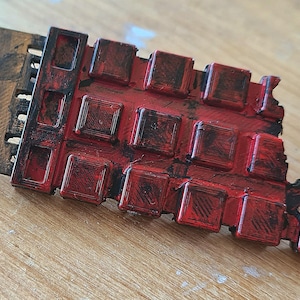 May include: A 3D printed model of a TARDIS, the time machine from the Doctor Who television series. The model is red and black, with a weathered and distressed finish, giving it a vintage look.