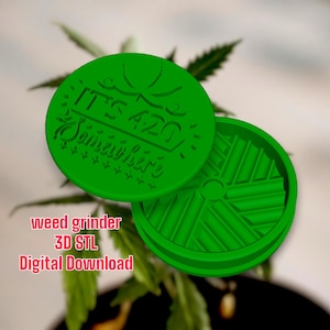 May include: A green 3D printed weed grinder with the text "It's 420 Somewhere" on the top. The grinder is made of two parts, a top and a bottom. The bottom part has a circular design with a hole in the centre.