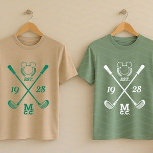 May include: Two short-sleeved t-shirts, one tan and one green, hanging on wooden hangers. Each shirt features a golf-themed design with crossed golf clubs, a Mickey Mouse head, the text "EST. 1928," and "M.C.C."
