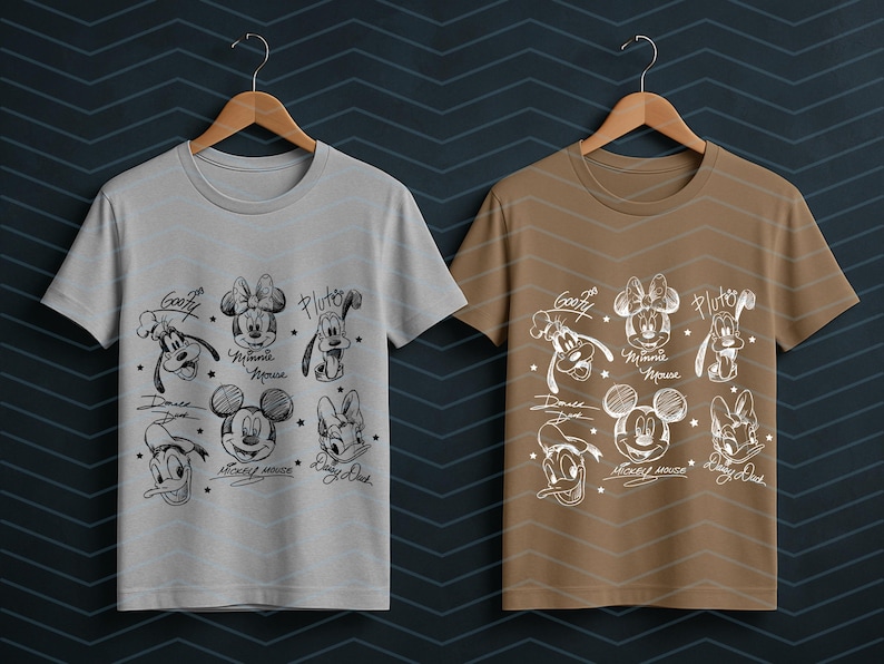 May include: Two t-shirts, one light gray and one brown, each displaying a black and white sketch of Disney characters. The designs include Mickey Mouse, Minnie Mouse, Goofy, Pluto, and Donald Duck, with their names and signatures.