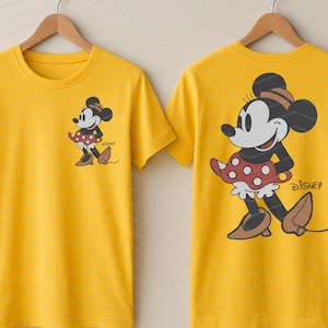 K&ouml;nnte beinhalten: Gelbes T-Shirt mit Minnie Mouse-Motiv auf Vorder- und R&uuml;ckseite. Das Design zeigt Minnie in einem roten Polka-Dot-Kleid, einem schwarzen Oberteil und braunen Schuhen. Das Disney-Logo ist ebenfalls sichtbar.