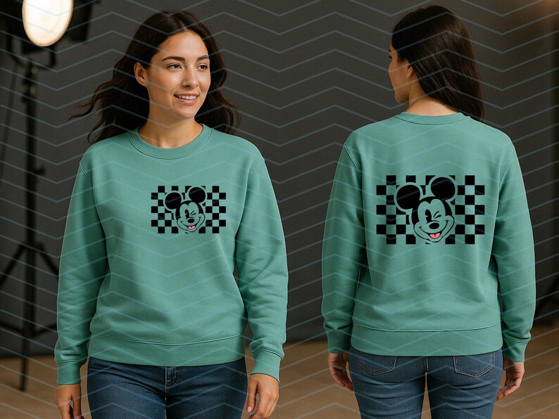 May include: A teal green sweatshirt with a black and white checkered graphic of Mickey Mouse winking. The graphic is centered on the front of the sweatshirt.
