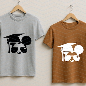 May include: Two short-sleeved t-shirts on wooden hangers. One is gray, the other is brown. Each shirt features a graphic of a mouse head wearing a graduation cap and sunglasses with heart-shaped lenses.