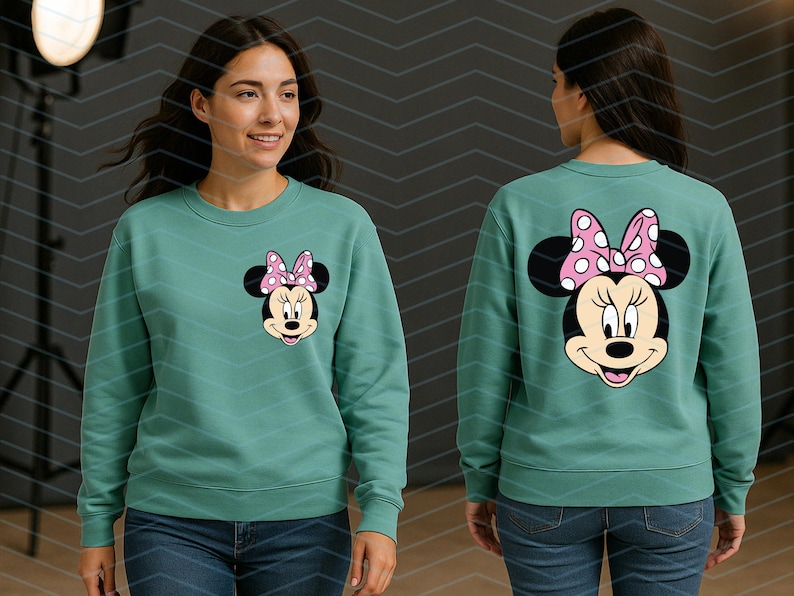May include: Teal sweatshirt featuring Minnie Mouse. The front displays Minnie's face with a pink polka dot bow. The back of the sweatshirt shows Minnie's face and bow. The sweatshirt is a crew neck style and is paired with blue jeans.
