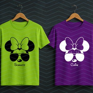 May include: Two short-sleeved t-shirts, one lime green and one purple, each featuring a cartoon mouse face with sunglasses and a bow. The green shirt has the name "Scarlett" and the purple shirt has the name "Claire" printed below the face.