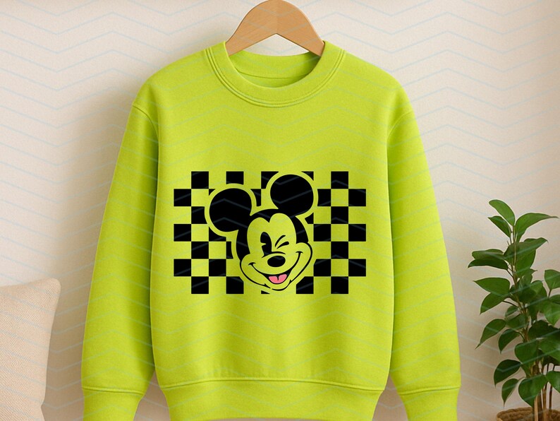 May include: A bright green sweatshirt with a black and white checkered pattern and a cartoon image of Mickey Mouse with a wink.