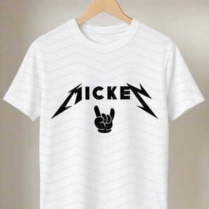 May include: White t-shirt with a black graphic design. The design features the word "MICKEY" in a stylized font, with a hand gesture below. The shirt is hanging on a wooden hanger.