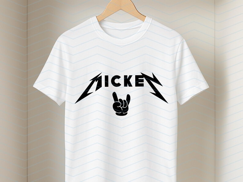 May include: White t-shirt with a black graphic design. The design features the word "MICKEY" in a stylized font, with a hand gesture below. The shirt is hanging on a wooden hanger.
