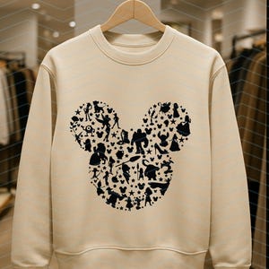 May include: A beige crewneck sweatshirt featuring a large black graphic on the chest. The graphic is shaped like a mouse head silhouette and is composed of numerous small black silhouettes of various animated characters, stars, and small mouse icons.