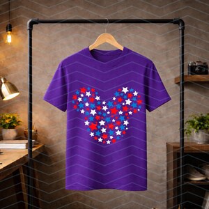 May include: A purple short-sleeved t-shirt featuring a central graphic composed of numerous small red, white, and blue stars arranged to form the distinct silhouette of a mouse head shape. The shirt has a crew neckline and is displayed on a hanger.