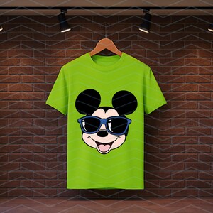 K&ouml;nnte beinhalten: Ein helles, limettengr&uuml;nes Kurzarm-T-Shirt mit einem Grafikdruck von Mickey Mouse, der eine dunkelblaue Sonnenbrille tr&auml;gt. Das Design zeigt die ikonischen runden Ohren, ein l&auml;chelndes Gesicht mit offenem Mund und eine blaue Brille.