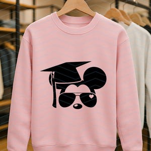 May include: A light pink crewneck sweatshirt featuring a black graphic of a mouse wearing sunglasses, a graduation cap, and a heart. Other sweatshirts are visible in the background.