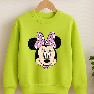 May include: A lime green sweatshirt featuring a Minnie Mouse graphic. The graphic shows Minnie's face with black ears and a pink bow with white polka dots. The sweatshirt is hanging on a wooden hanger.