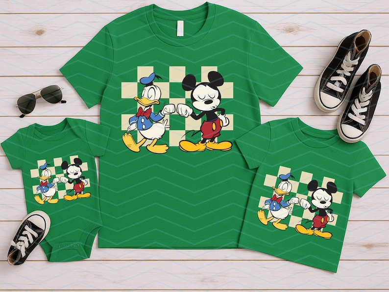 May include: Green t-shirts and a onesie featuring Donald Duck and Mickey Mouse. The shirts have a checkered background and are paired with black sneakers and sunglasses. A family matching outfit.