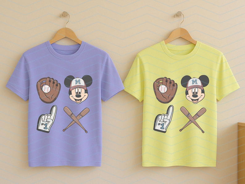 May include: Two t-shirts with a purple and yellow color scheme. Both shirts feature a cartoon Mickey Mouse wearing a baseball cap with the letter "M" on it. The shirts also feature a baseball glove, a baseball, and two crossed baseball bats.