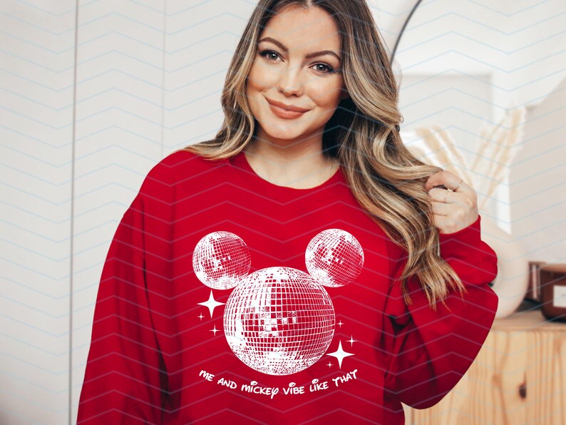 Puede incluir: Sudadera roja con un dise&ntilde;o de Mickey Mouse blanco con bolas de discoteca. El texto "Me and Mickey vibe like that" est&aacute; impreso debajo del dise&ntilde;o.
