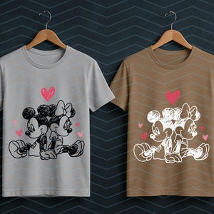 Peut inclure: Deux t-shirts, un gris et un marron, chacun avec un croquis de Mickey et Minnie Mouse s'embrassant, avec des c&oelig;urs roses. Les motifs sont imprim&eacute;s sur des t-shirts &agrave; col rond et &agrave; manches courtes.