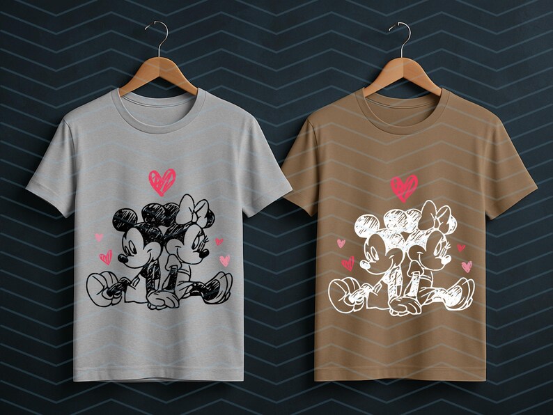 Peut inclure: Deux t-shirts, un gris et un marron, chacun avec un croquis de Mickey et Minnie Mouse s'embrassant, avec des c&oelig;urs roses. Les motifs sont imprim&eacute;s sur des t-shirts &agrave; col rond et &agrave; manches courtes.