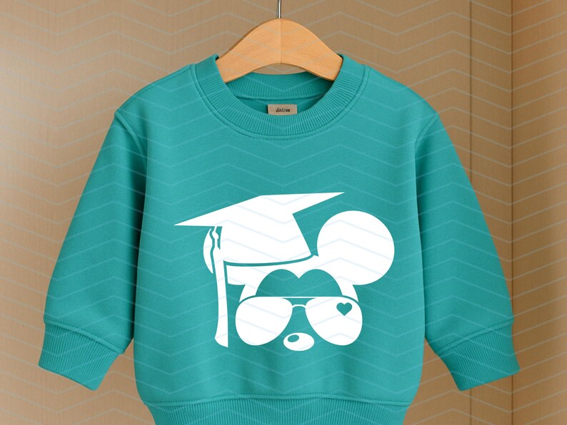 May include: Teal sweatshirt featuring a white graphic of a mouse wearing a graduation cap and sunglasses with a heart detail. The sweatshirt has a crew neck and long sleeves. The design is centered on the front of the garment.
