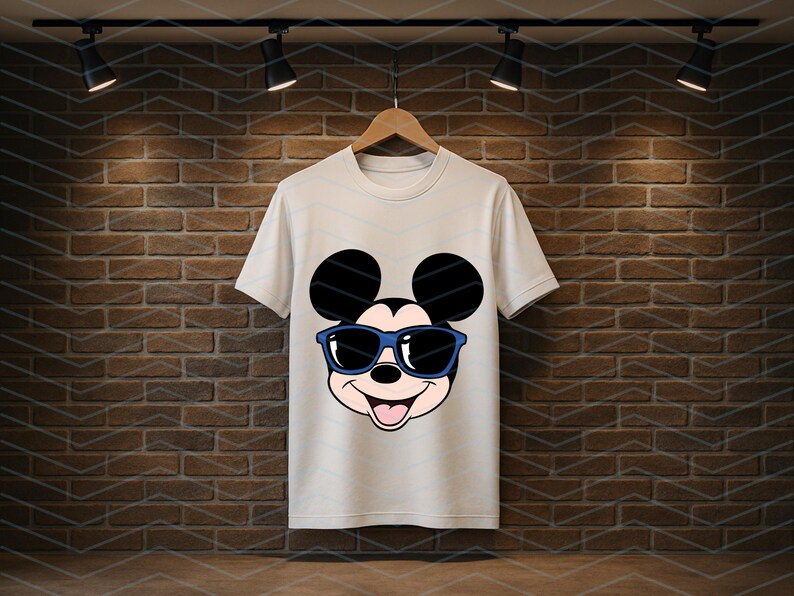 K&ouml;nnte beinhalten: Ein wei&szlig;es kurz&auml;rmeliges T-Shirt mit einem Grafikdruck des Gesichts von Mickey Mouse, der eine blau umrandete Sonnenbrille tr&auml;gt. Die Figur hat schwarze Ohren, ein helles Gesicht und einen l&auml;chelnden Ausdruck mit sichtbarer Zunge.
