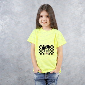 May include: A young person wearing a bright yellow t-shirt with a black and white checkered design featuring Mickey Mouse's face.