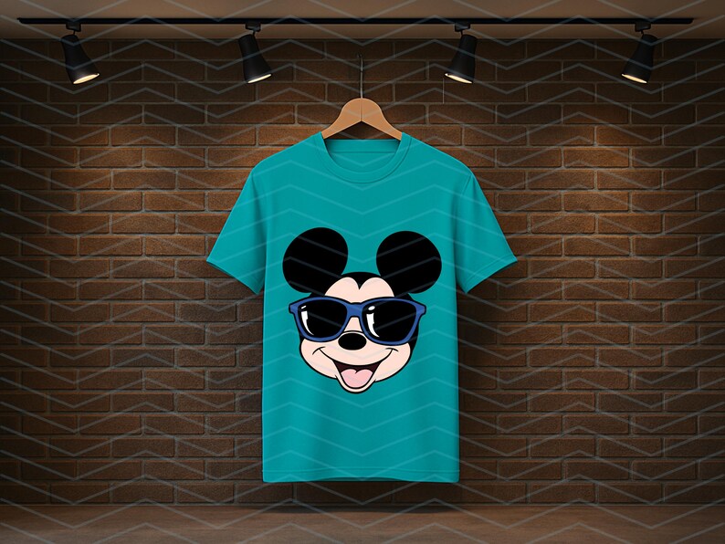 K&ouml;nnte beinhalten: Ein kurz&auml;rmeliges T-Shirt in Petrol mit einem Grafikdruck von Mickey Mouse, der eine dunkelblaue Sonnenbrille tr&auml;gt. Das Charakterdesign zeigt die ikonischen runden Ohren, ein l&auml;chelndes Gesicht mit offenem Mund und eine schwarze Nase.
