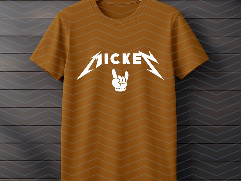 May include: Mustard-colored t-shirt with a white graphic. The graphic features the word "MICKEY" in a stylized font with lightning bolt accents and a hand making a rock and roll gesture.
