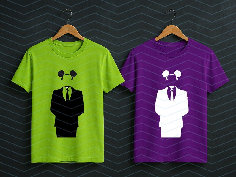 May include: A lime green t-shirt and a purple t-shirt, each featuring a graphic print of a suit jacket, a necktie, and a pair of circular ears. The lime green shirt displays the graphic in black, while the purple shirt displays the graphic in white.
