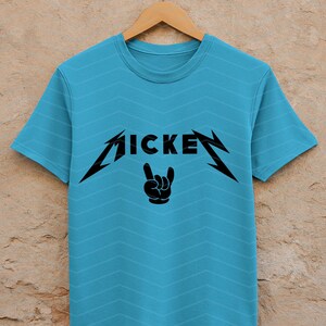 May include: A light blue t-shirt with a black graphic design. The design features the word "MICKEY" in a stylized font, with a hand gesture below. The shirt is hanging on a wooden hanger.