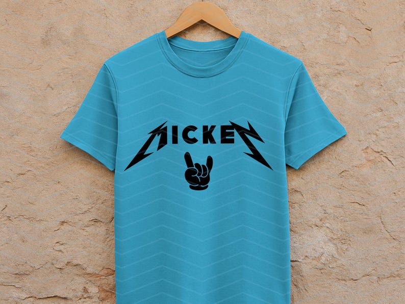 May include: A light blue t-shirt with a black graphic design. The design features the word "MICKEY" in a stylized font, with a hand gesture below. The shirt is hanging on a wooden hanger.