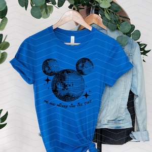Puede incluir: Una camiseta azul real con un gr&aacute;fico negro de la cabeza de Mickey Mouse hecha de bolas de discoteca. El texto "Me and Mickey vibe like that" est&aacute; impreso debajo del gr&aacute;fico.