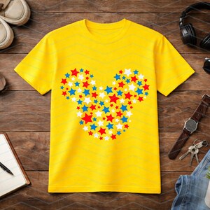 May include: A bright yellow short-sleeved t-shirt featuring a central graphic composed of numerous small red, white, and blue stars arranged to form the distinct silhouette of a mouse head shape with two circular ears and a rounded face.