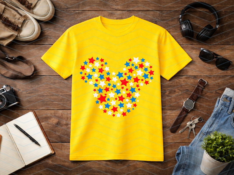 May include: A bright yellow short-sleeved t-shirt featuring a central graphic composed of numerous small red, white, and blue stars arranged to form the distinct silhouette of a mouse head shape with two circular ears and a rounded face.