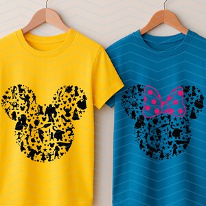 May include: A yellow t-shirt and a blue t-shirt, both featuring a black silhouette of a mouse head shape filled with various character figures. The blue t-shirt includes a pink polka-dot bow graphic positioned above the mouse head silhouette.