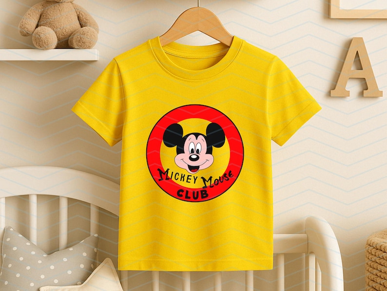 May include: A bright yellow short-sleeved t-shirt featuring a circular graphic on the chest. The graphic contains a red border, a yellow center, and the face of Mickey Mouse with the black text Mickey Mouse Club printed underneath the character.