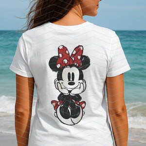May include: White t-shirt featuring a distressed graphic of Minnie Mouse. The cartoon character is depicted with a red bow with white polka dots. The shirt is a classic crew neck style, perfect for casual wear.