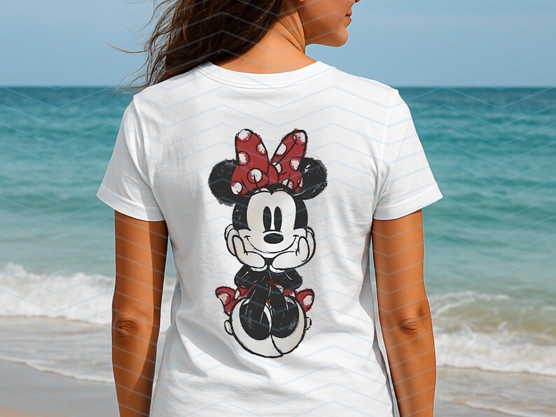 May include: White t-shirt featuring a distressed graphic of Minnie Mouse. The cartoon character is depicted with a red bow with white polka dots. The shirt is a classic crew neck style, perfect for casual wear.