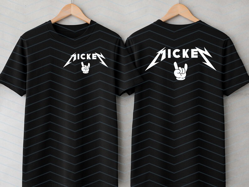 May include: Black short-sleeve t-shirts with a white graphic design. The design features the word "MICKE" in a stylized font with a hand making a rock and roll gesture. The shirts are displayed on wooden hangers.