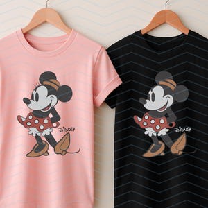 K&ouml;nnte beinhalten: Zwei T-Shirts, eines rosa und eines schwarzen, jeweils mit einem Minnie Mouse-Motiv. Die Grafik zeigt Minnie in einem roten Polka-Dot-Rock, braunen Schuhen und einem passenden Hut. Das Disney-Logo ist darunter gedruckt.