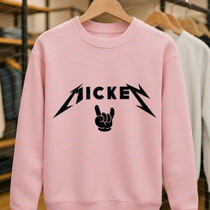 May include: A light pink crew neck sweatshirt with the word "MICKE" in a black, stylized font, with a rock and roll hand gesture graphic. Other sweatshirts are visible in the background.